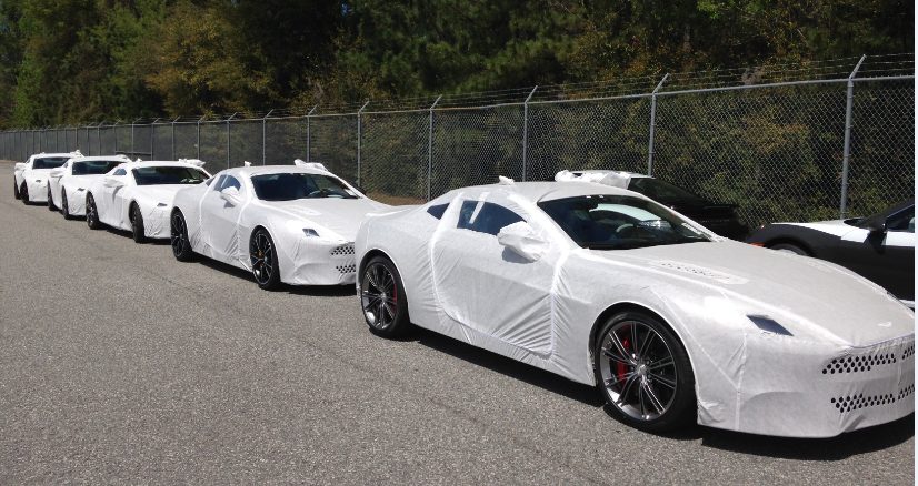 Row of white vehicles covered in protective wrap, lined up on the yard