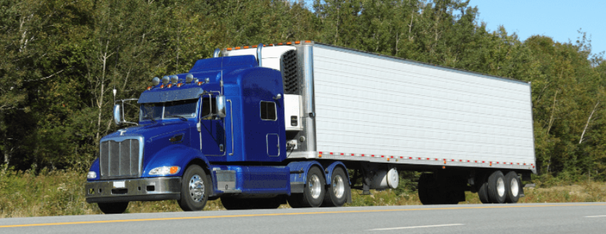 Blue semi tractor with white trailer on the road