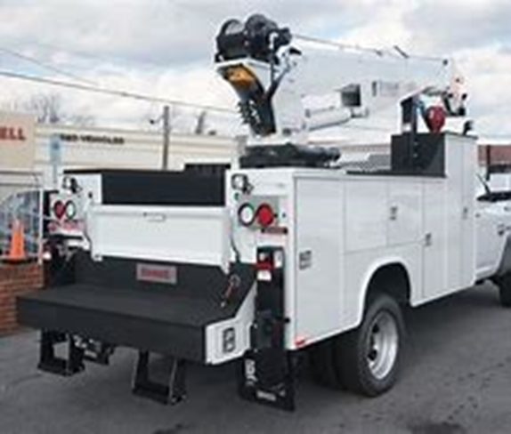 Utility truck with crane and service body parked at a job site